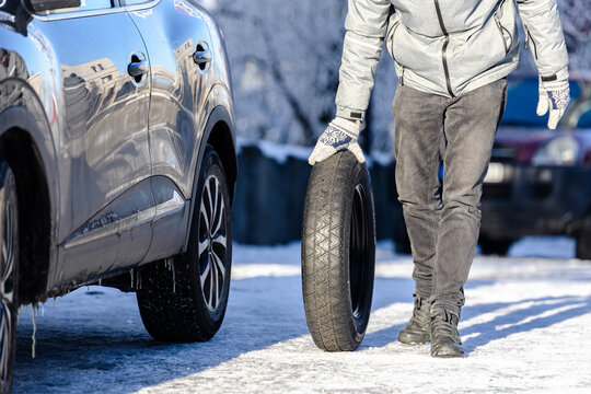 Man with spare wheel outdoors. Winter scene. Flat tire concept.