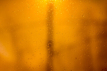 Window with rain drops under bright light, blurred background