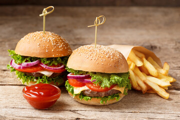 Two burgers, french fries, sauces on a wooden background. Fast food, homemade hamburgers