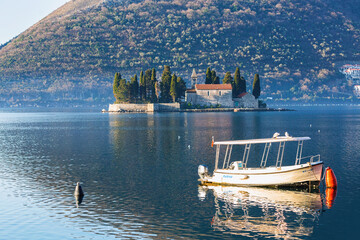 Anchored tourist boat at calm water of Bay of Kotor. Saint George Island (Ostrvo Sveti Dorde) at...
