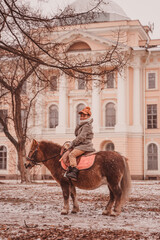 Naklejka premium boy looks around while sitting astride a pony