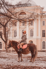 boy looks around while sitting astride a pony