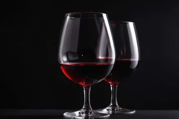 Fotobehang Close-up Red wine in a clear glass against a pure black color background. elegance and rich colors © Giuseppe Cammino