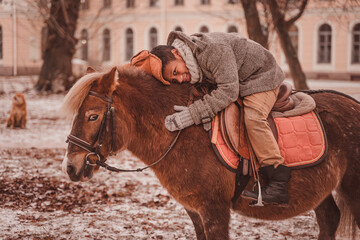 Naughty little rider hugs a pony while riding a pony