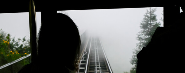 Panorama rear view Asian lady at front driver cabin of electric tram watching the foggy misty...
