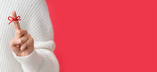 Woman with red bow on index finger against color background with space for text. Reminder concept
