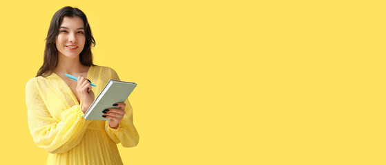 Pretty young woman writing reminder in notebook on yellow background with space for text