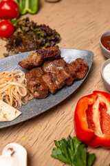 Uzbek national dish. Juicy meat on skewers with vegetables and herbs on wooden table.