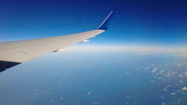 Airplane wing view window shot right panning flying high altitude above sea ocean water