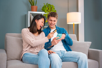 Multiracial Young Couple Sitting On Sofa Happy Entering Credit Card Number On Tablet To Make Easy...
