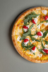 Freshly baked pizza with strawberries, cream cheese and arugula on a white plate. view from above