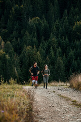 Man and woman jogging through the forested mountains in fitness gear