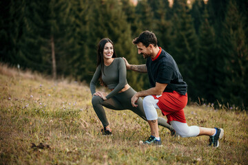 Diverse couple prepping for a jog in the mountainous terrain draped with pine trees
