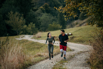 Obraz premium Fitness-focused couple running side by side on a mountain trail, embracing the great outdoors