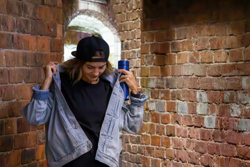 Fototapeta na wymiar Blonde girl in a denim jacket with long hair, cheerful, woman, young blonde near a brick wall, beautiful smile, fashionable outfit. Sexually carefree, in nature. Cheerful and happy.