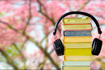 Relaxing with audiobooks during springtime season with heap of books and vintage headphones....