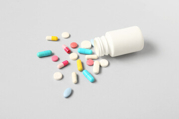 Jar with many different pills on grey background
