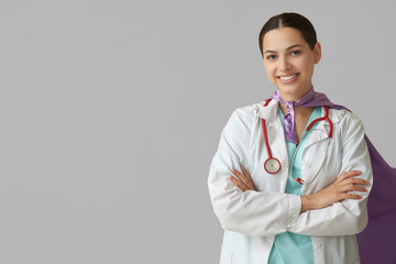 Beautiful female doctor in superhero costume on white background