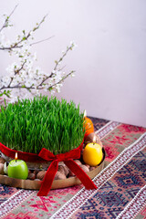 Beautiful Novruz tray on rug with semeni - wheat grass with red ribbon, festive candles on national...