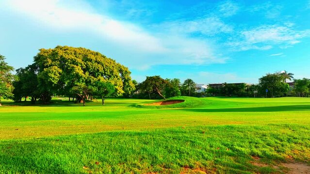 Outdoor sports games. Panoramic views of the golf course. Lawn with sand traps on green grass. Background of a green golf course on a sunny day. Vacation and relaxation concept.