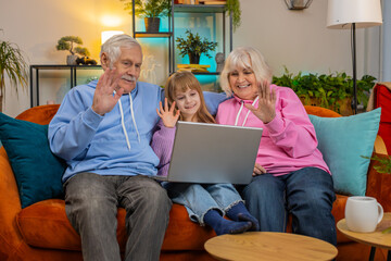 Caucasian grandfather, grandmother and granddaughter making video call online on laptop at home....