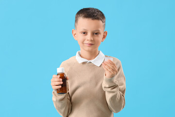 Ill little boy with cough syrup on blue background
