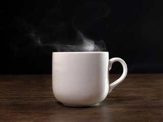 Smoke vape fog flowing out of white ceramic coffee cup on dark black background