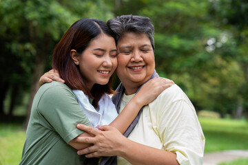Obraz premium Attractive Senior mother and daughter working out together in the morning exercise in the park. The daughter Talks, smile and laughs with her mom, a senior caregiver, and a happy family concept.