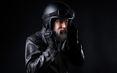 Portrait d'un motard homme avec un casque noir et une veste en cuir et des lunettes de protection...