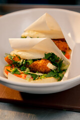 close-up of ready-made buns with shrimp and vegetables in paper packaging laid out on white tray