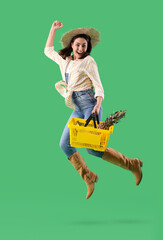 Female farmer with shopping basket of fruits jumping on green background