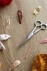 Wooden hairbrush, scissors and various headbands, hair clips and scrunchies on wooden background. Selective focus.