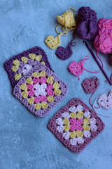 Granny squares crocheting in process. Colorful Afghan squares pattern close up photo. Grey background with copy space.  
