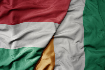 big waving national colorful flag of cote divoire and national flag of hungary .