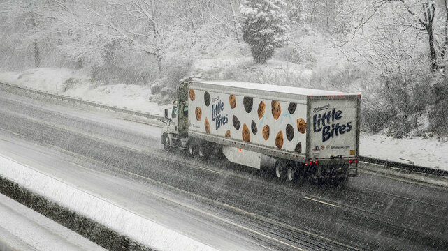 NORWALK, CT, USA - FEBRUARY 13, 2024: Truck from Entenmann's company with Little Bites on I-95 during  snowstorm in February 2024 on East Coast