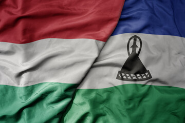 big waving national colorful flag of lesotho and national flag of hungary .
