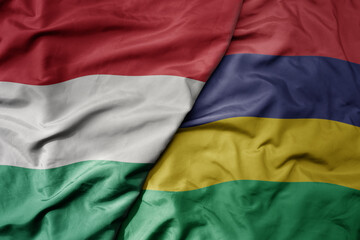 Obraz premium big waving national colorful flag of mauritius and national flag of hungary .