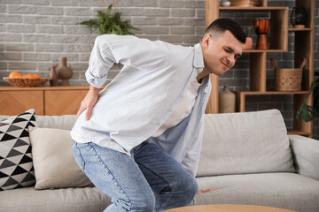 Young man suffering from back pain at home