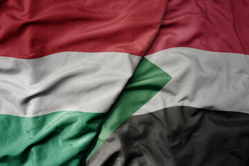 big waving national colorful flag of sudan and national flag of hungary .