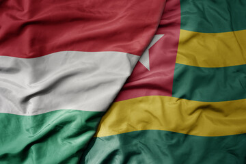 Obraz premium big waving national colorful flag of togo and national flag of hungary .