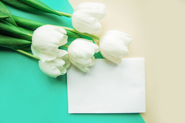 White tulips and white mockup blank on yellow and green background. Easter or Mother's Day greeting card. Copy space for the text