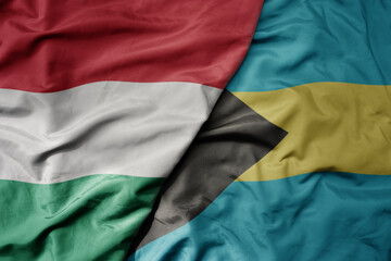 Obraz premium big waving national colorful flag of bahamas and national flag of hungary .