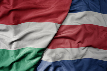 big waving national colorful flag of costa rica and national flag of hungary .