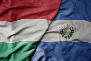 big waving national colorful flag of el salvador and national flag of hungary .