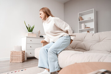 Mature woman with hemorrhoids sitting on sofa at home