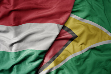big waving national colorful flag of guyana and national flag of hungary .