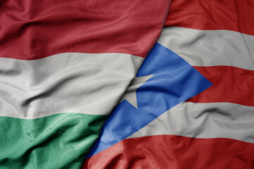 Obraz premium big waving national colorful flag of puerto rico and national flag of hungary .