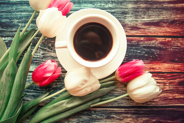Coffee cup and tulips on wooden background