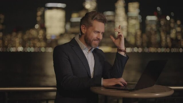 Businessman working on laptop at night with neon street lights in New York City. Business man in night Ney York. Business man using laptop outdoor. Business success in night city. Night Business.