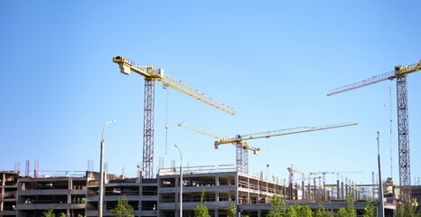 Many construction cranes standing near multi-storey buildings at site background. Sale of...